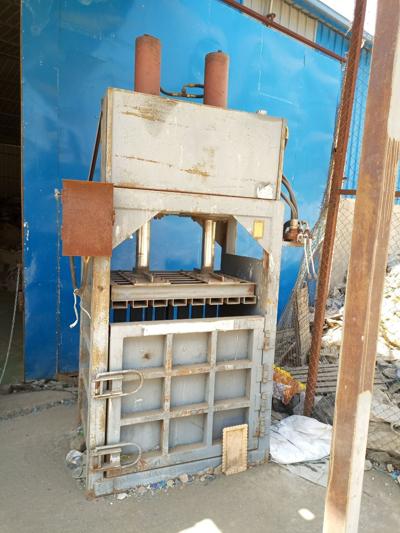 vertical hydraulic baling machine used to compress materials for recycling.